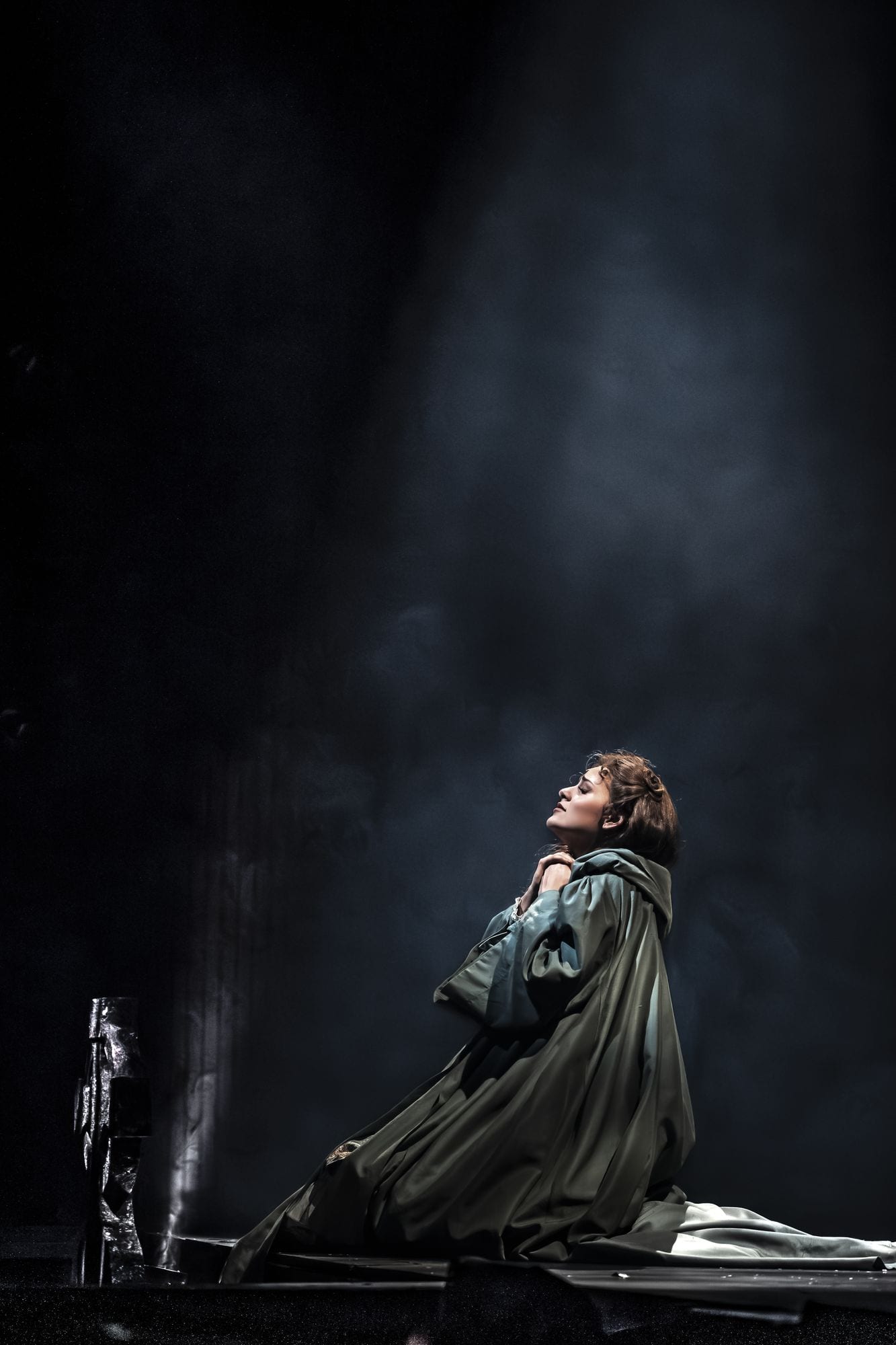 Christine Daaé arrodillada entre humo de escena bajo un cenital estrecho
