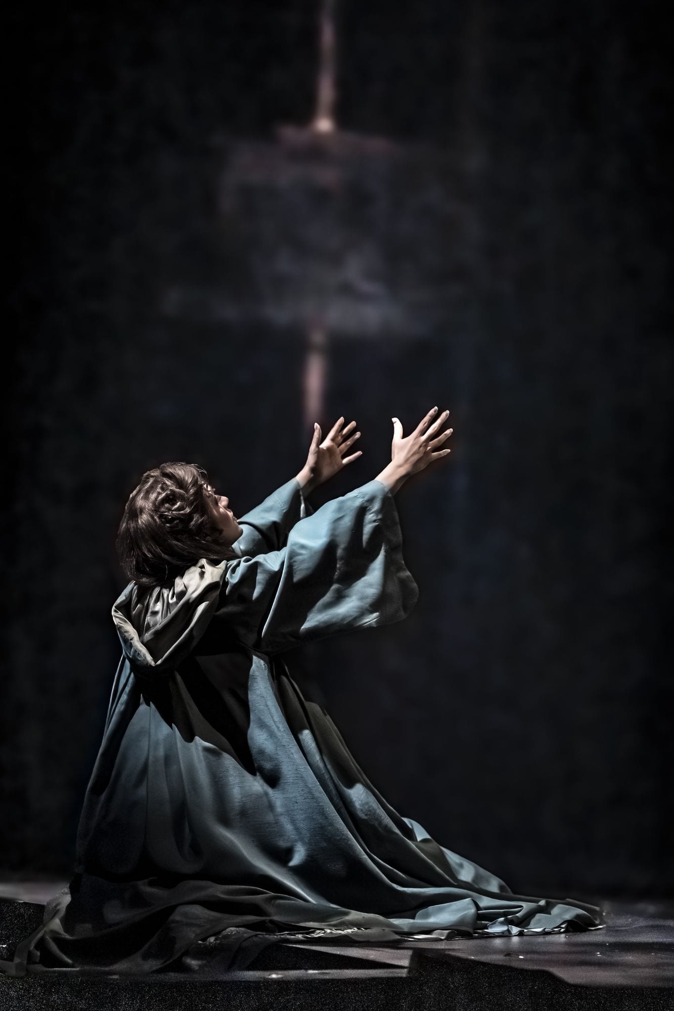 Christine Daaé de rodillas con los brazos abiertos, iluminada desde arriba