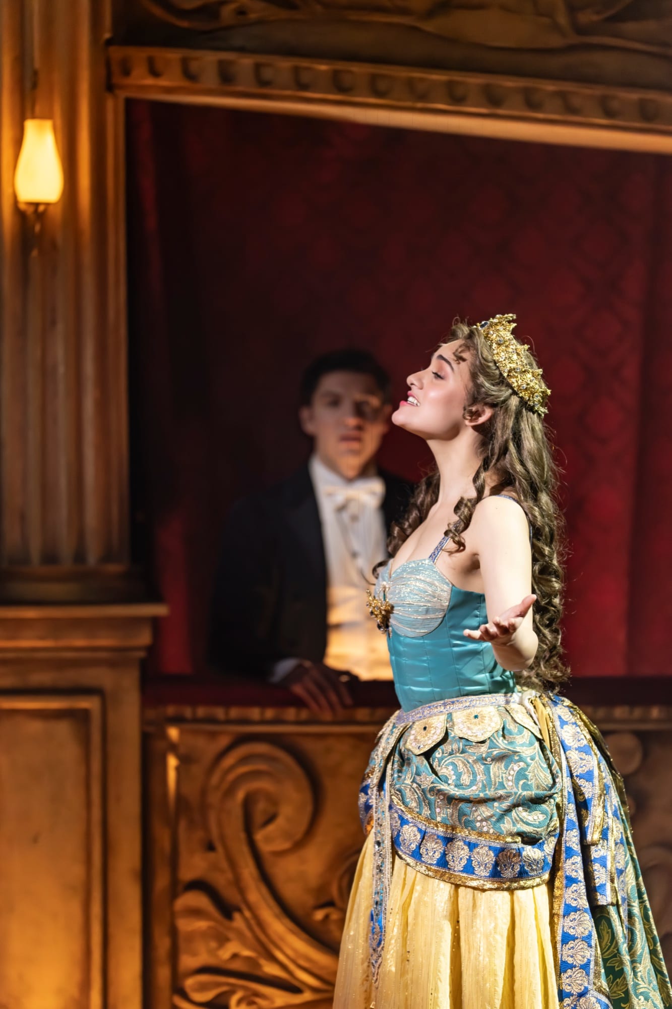 Christine Daaé singing in the golden costume, Raoul watching from the box behind her
