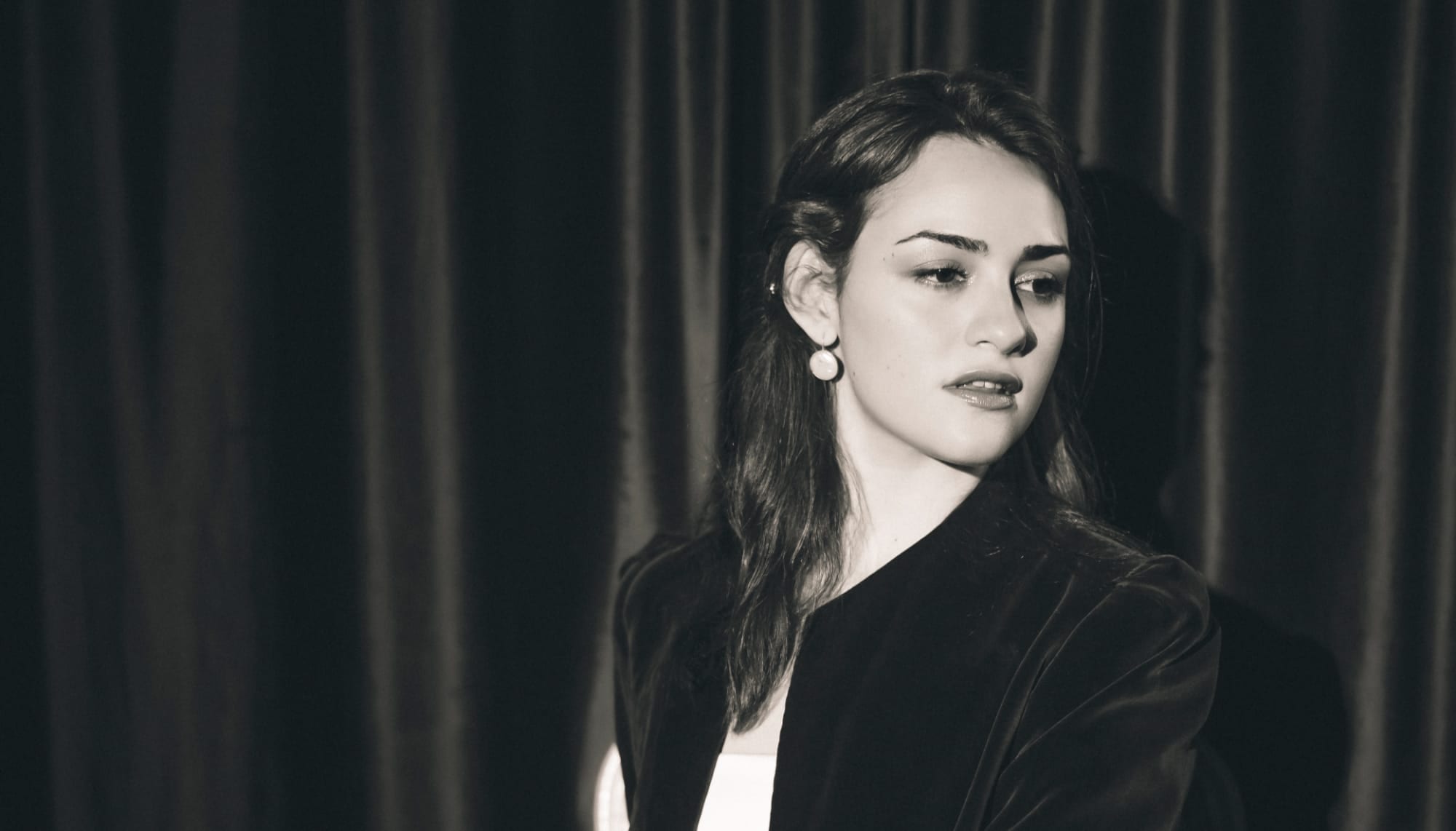 Black and white portrait against a stage curtain