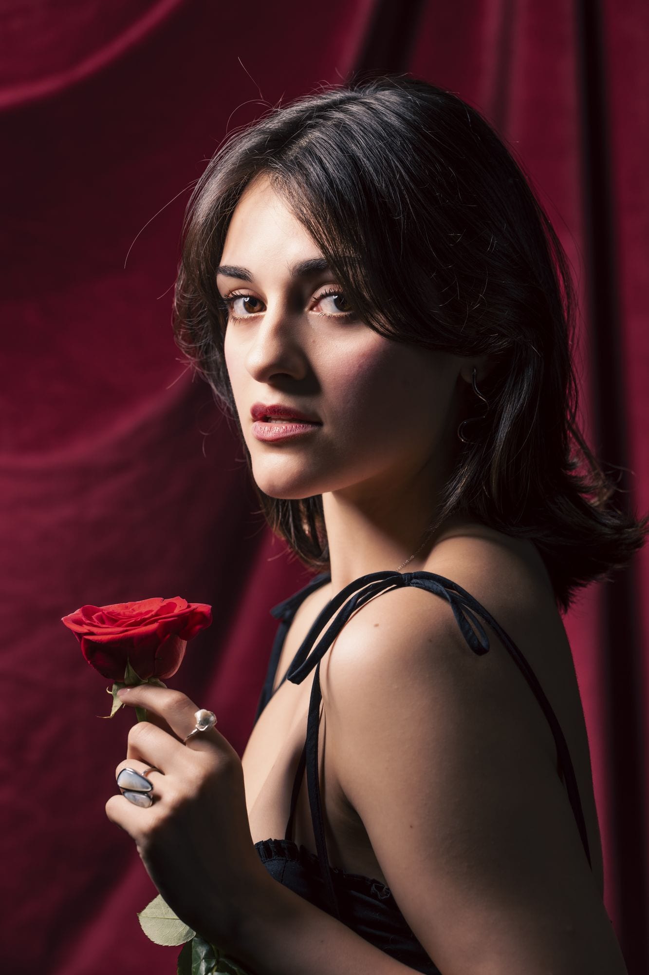 Mirando por encima del hombro con una rosa roja en la mano