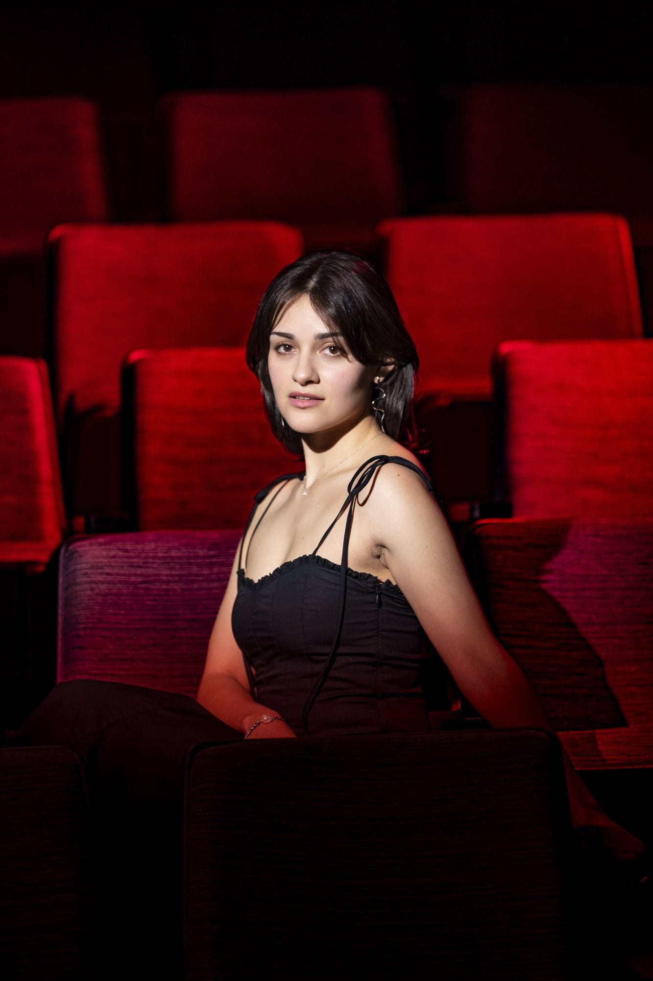 Sentada entre las butacas de terciopelo rojo de un teatro vacío