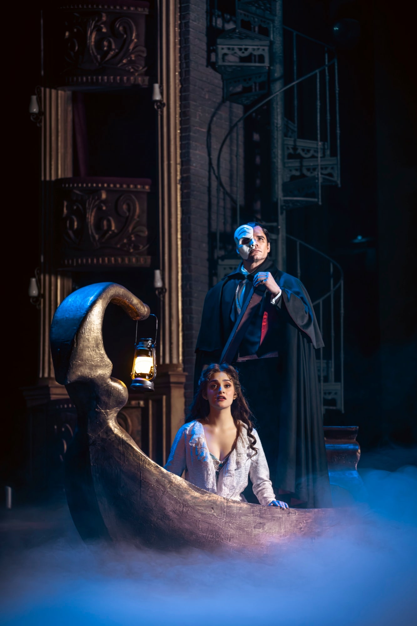 Christine Daaé in the boat, the Phantom standing behind her with the lantern, mist over the stage