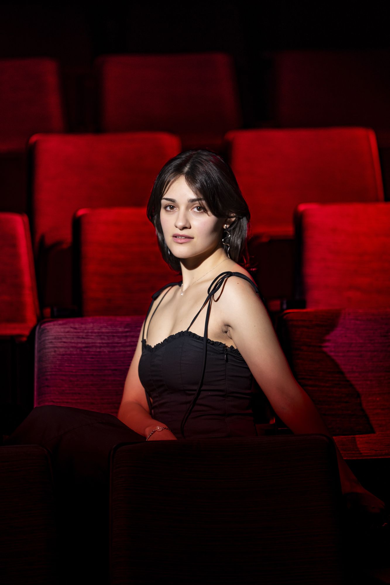 Seated among the red velvet seats of an empty theatre